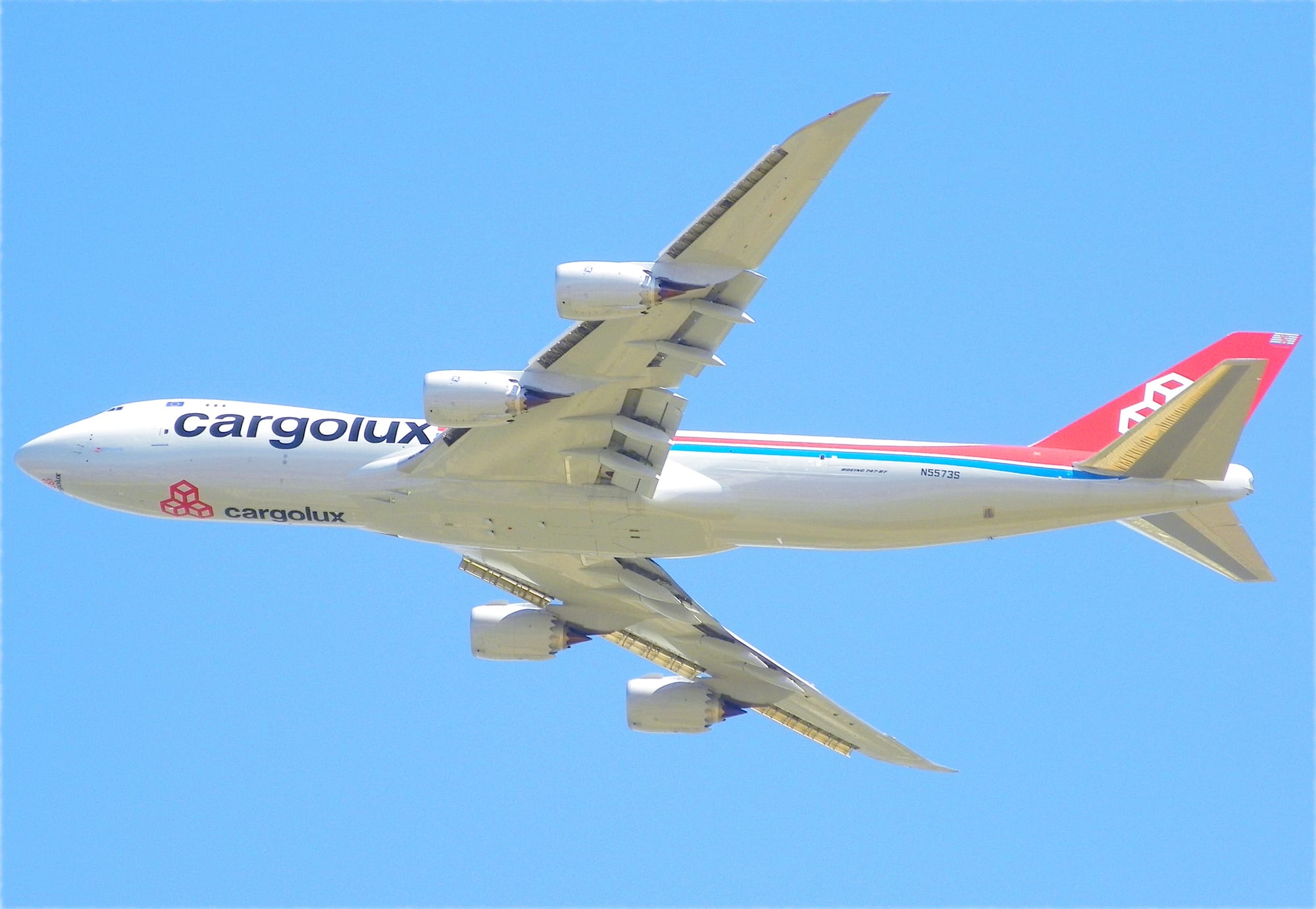 Cargolux Boeing 747-8 Freighter N5573S seen from below against a clear blue sky, showing the raked wingtips and four GEnx-2B engines